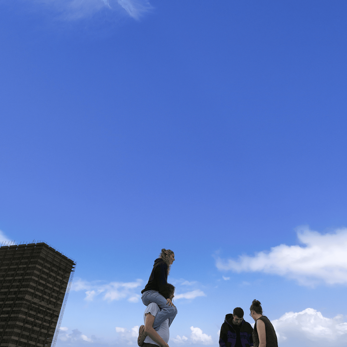 Album cover of a blue sky, with an apartment building in the background and a group of friends in the foreground.